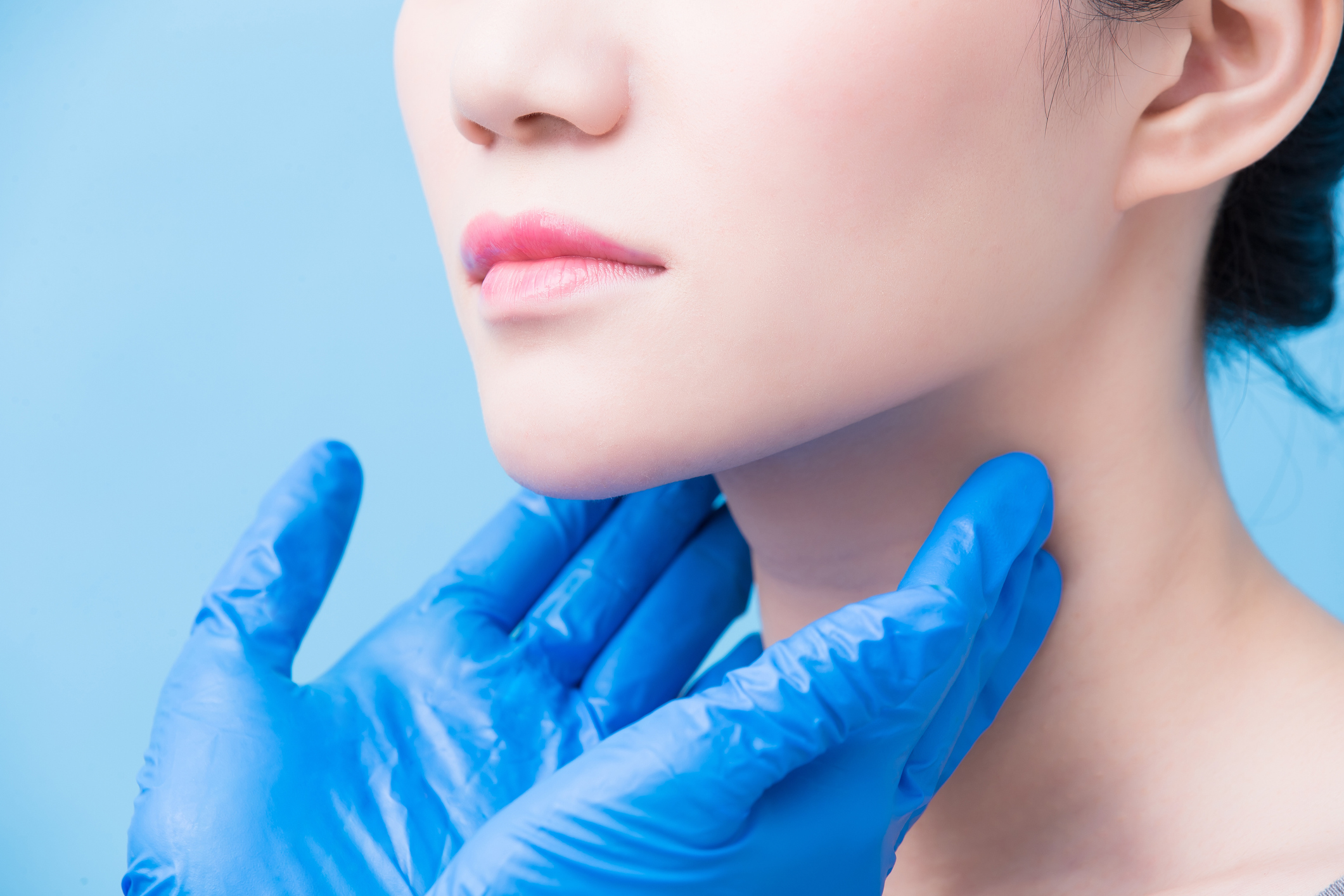 A dentist in blue gloves examines a woman for signs of mouth cancer