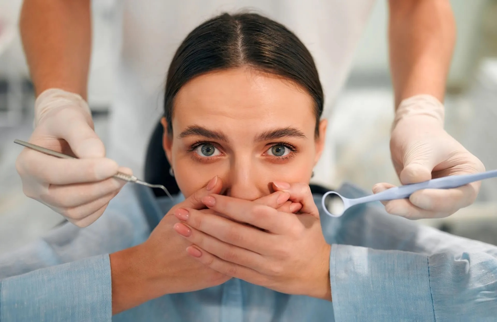 Nervous dental patient covering her mouth during a dental examination consultation.
