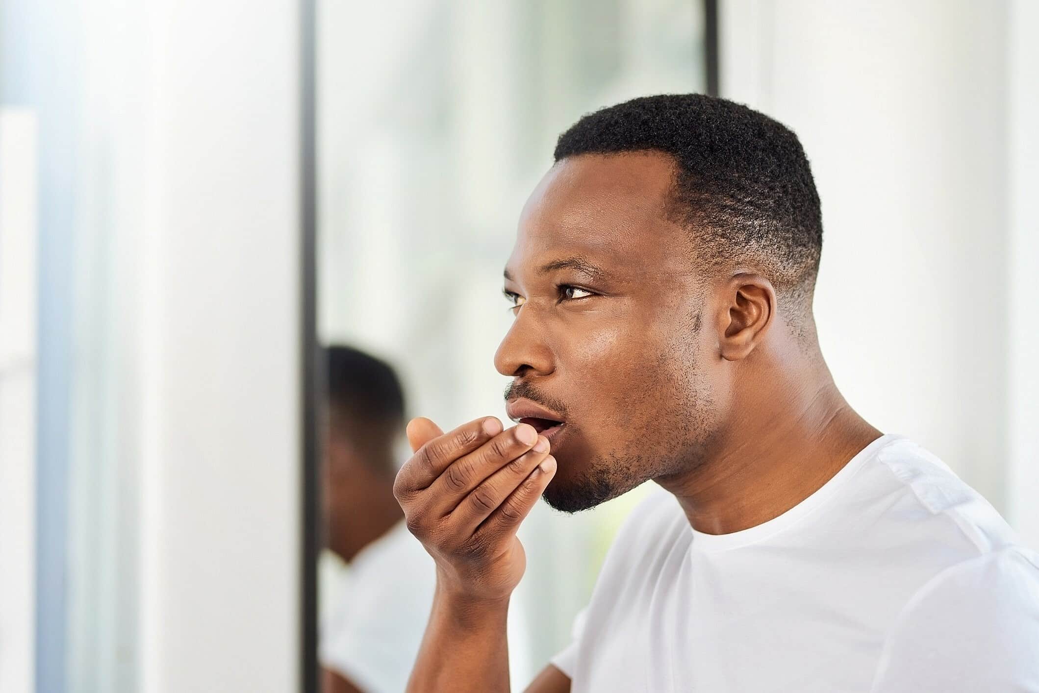 Man checking his breath by holding his hand near his mouth