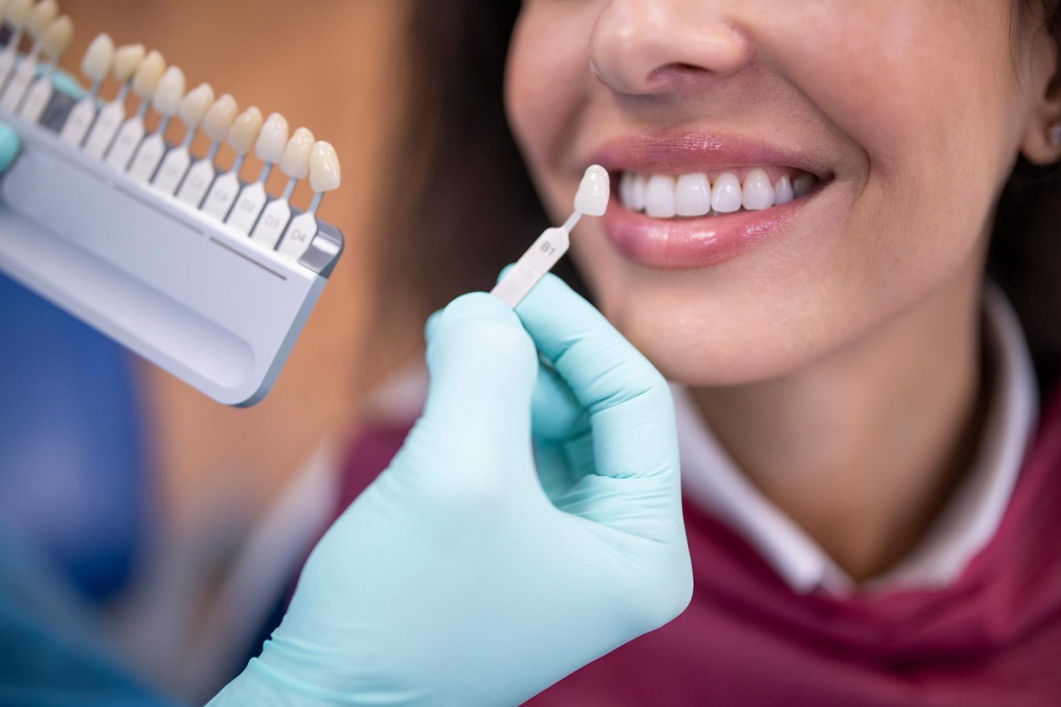 Woman smiling while getting her teeth replaced during a dental procedure