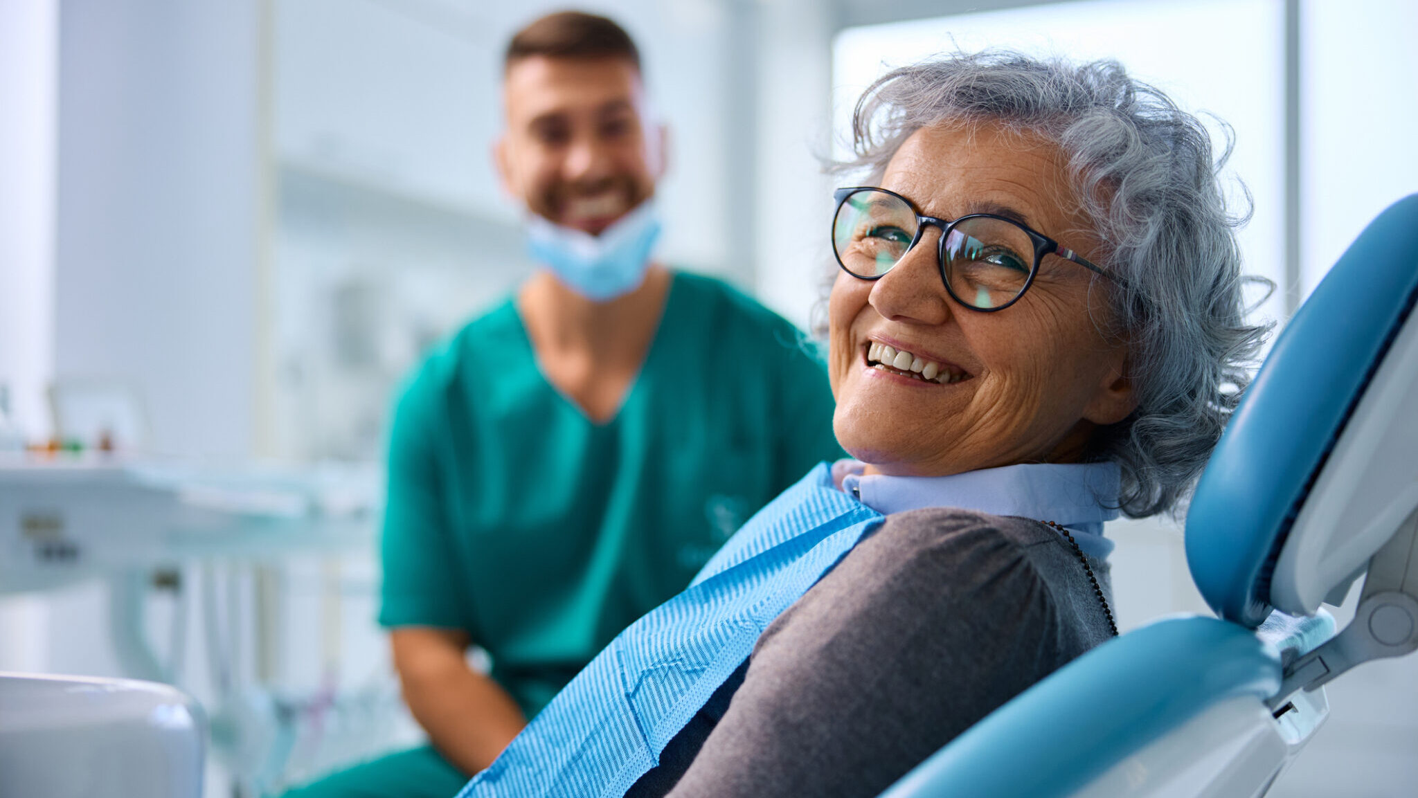 Smiling elderly patient relaxing in a dental chair during a clinic appointment.