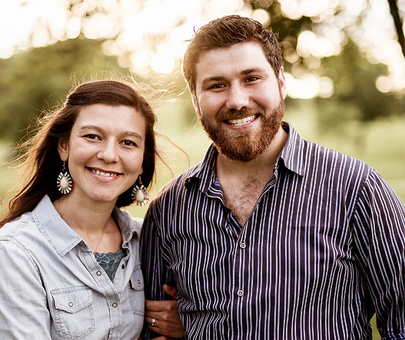 Couple smiling with sunlight shining behind them