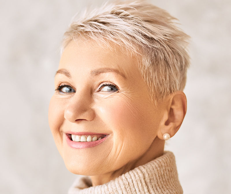 Older blonde woman smiling, showing white dental fillings