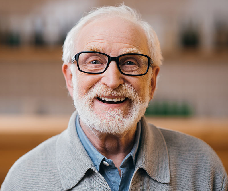 Older man wearing glasses smiling with white teeth