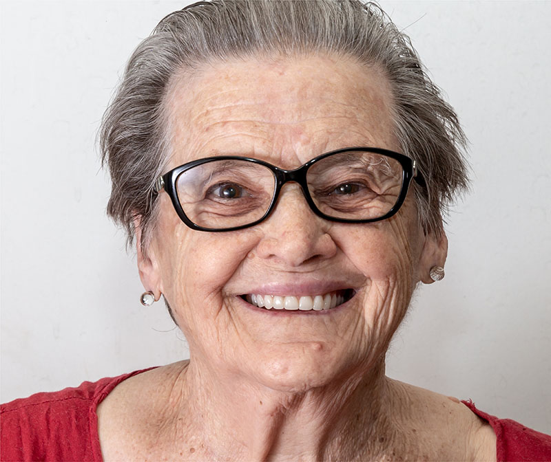 Older woman wearing glasses and a red top smiling