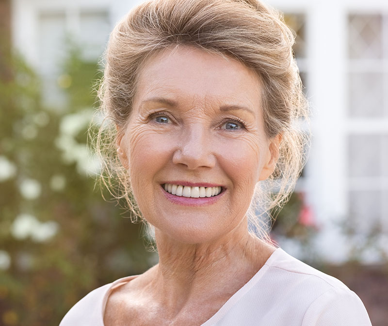 Older woman smiling and showing her dentures