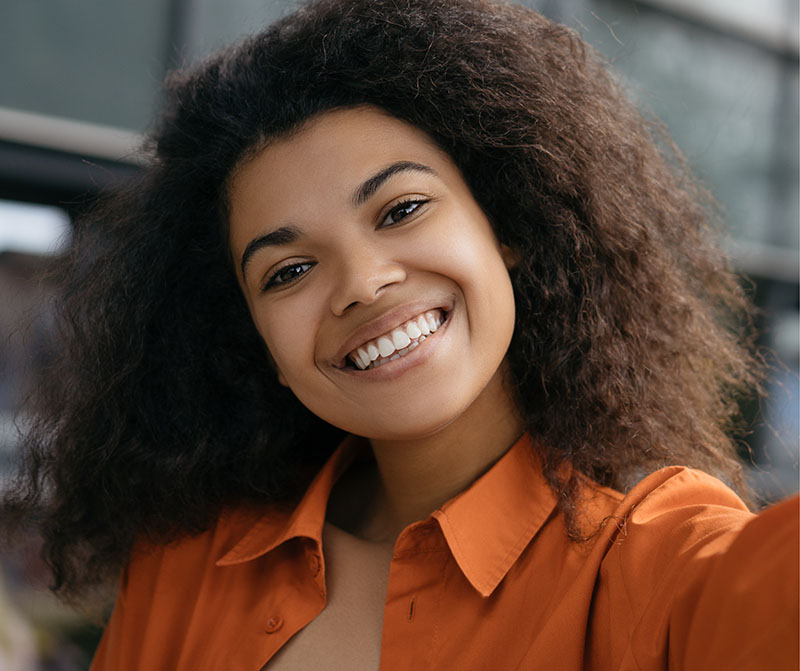 Woman smiling with white teeth wearing an orange jacket