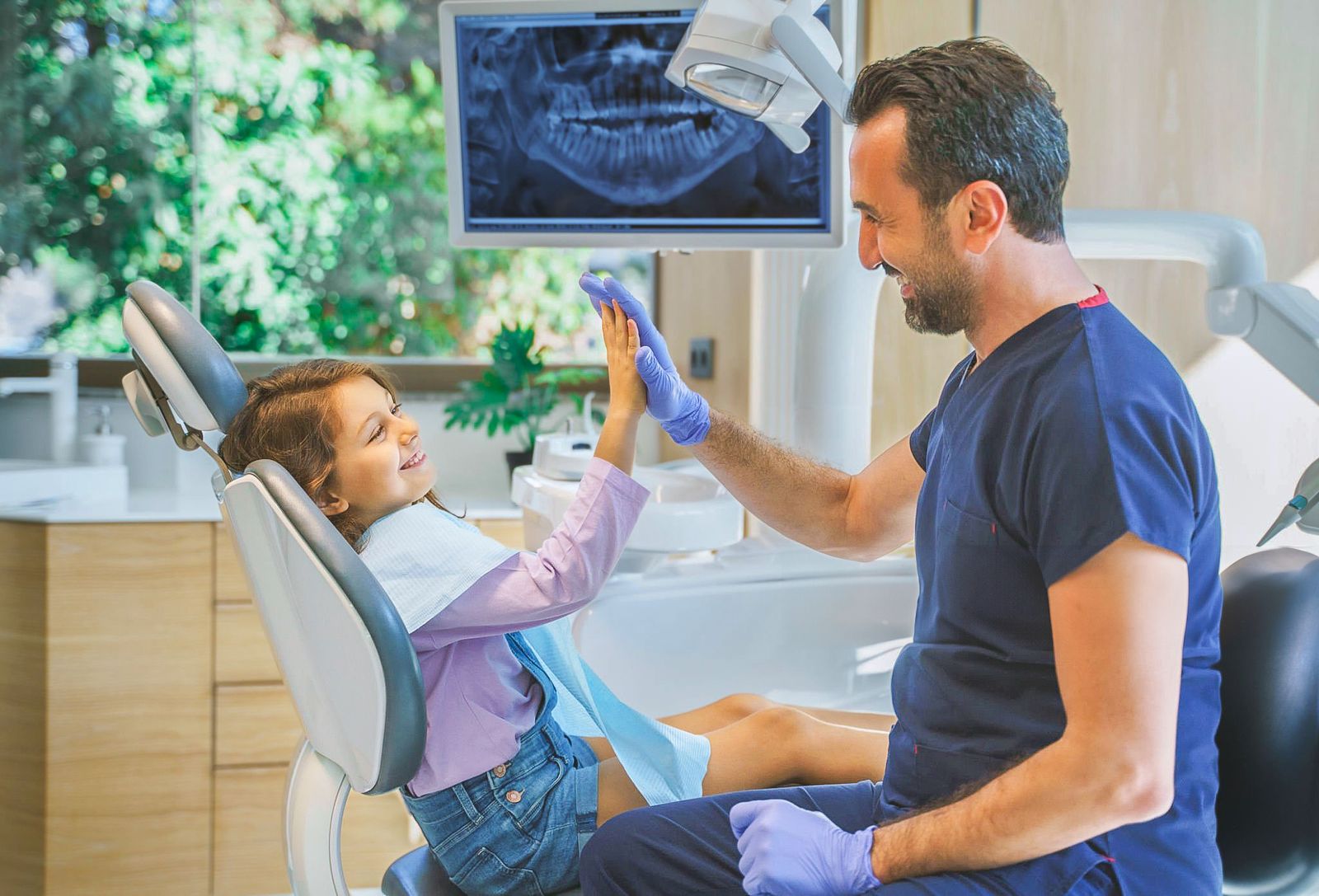 Dentist Hi-Fiving Child In Dentits Chair